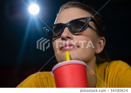 Woman having drinks while watching movie in theatre Woman having drinks while watching movie in theatre 34380624
