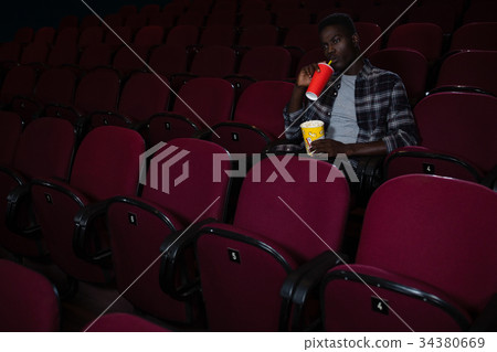 Man having cold drink while watching movie 34380669