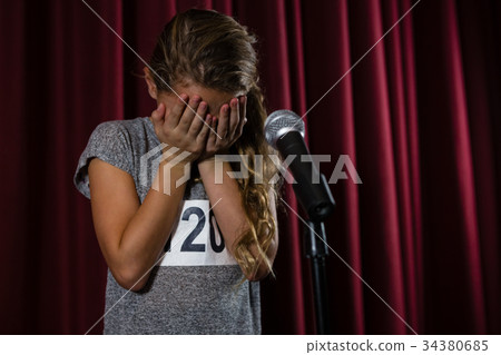 Girl covering her face with hand on stage Girl covering her face with hand on stage 34380685