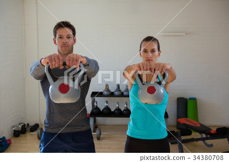 Portrait of confident athletes lifting kettlebells 34380708