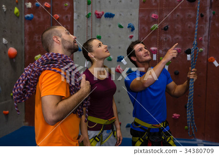 Male trainer guiding athletes in wall climbing Male trainer guiding athletes in wall climbing 34380709