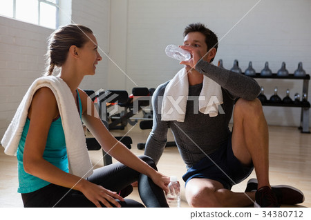 Athletes talking with drinking water in gym 34380712