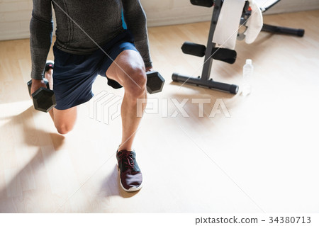 Low section of athlete lifting dumbbells in health club 34380713