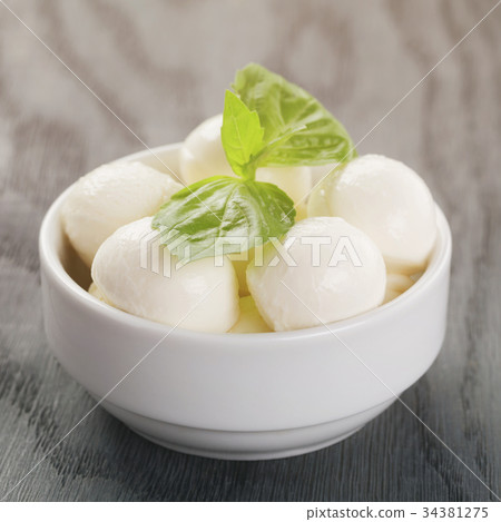 small balls of mozzarella in bowl with basil 34381275