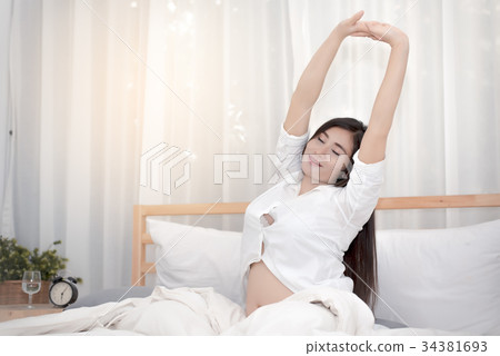 The pregnant woman waking up and stretching 34381693