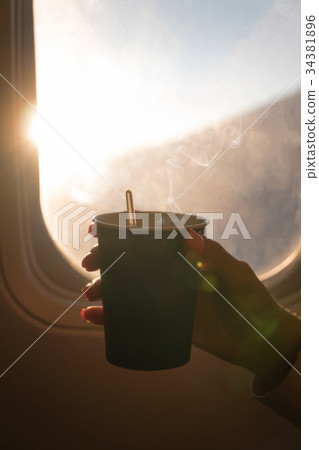 Girl is holding a glass of coffee in aircraft Girl is holding a glass of coffee in aircraft 34381896