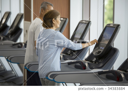 Senior couple walking on running machine 34383884