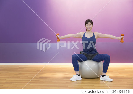 做啞鈴的婦女在平衡球行使 做啞鈴的婦女在平衡球行使 34384146