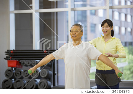 Trainer giving muscle training to senior men 34384575