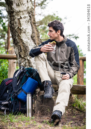 Hiker taking food break in shade of tree Hiker taking food break in shade of tree 34384618