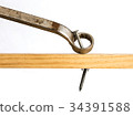 A wrench being used to pry a nail from wood 34391588