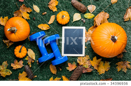 Blue dumbbells and autumn pumpkin with blackboard Blue dumbbells and autumn pumpkin with blackboard 34396936