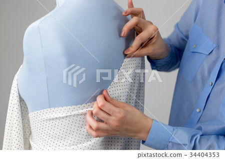 Seamstress measuring beautiful fabric on blue 34404353