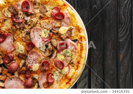 Top view of tasty pizza on dark wooden background Top view of tasty pizza on dark wooden background 34416391
