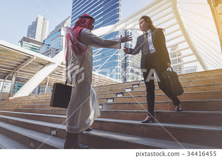Arab businessman and businesswoman handshaking Arab businessman and businesswoman handshaking 34416455
