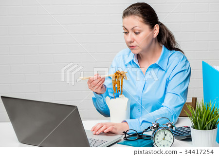 Accountant working on laptop and eating noodles 34417254