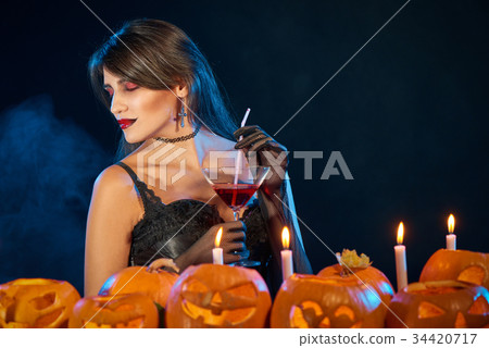 Sensual witch holding cocktail glass 34420717