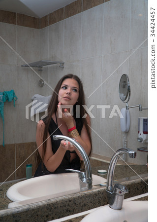 girl smears face with cream in the bathroom girl smears face with cream in the bathroom 34424457