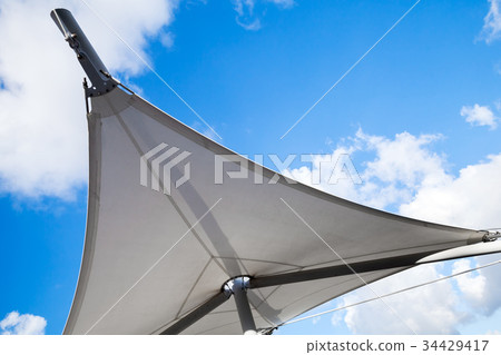 Awning in sail shape under cloudy sky Awning in sail shape under cloudy sky 34429417