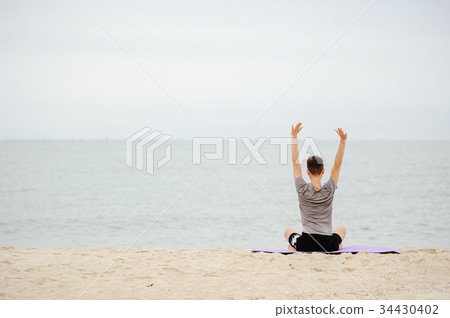 man practicing yoga on the beach in early morning. 34430402