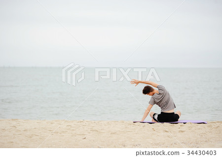 man practicing yoga on the beach in early morning. man practicing yoga on the beach in early morning. 34430403