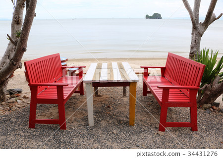 Red wooden table and chairs on the beach. 34431276