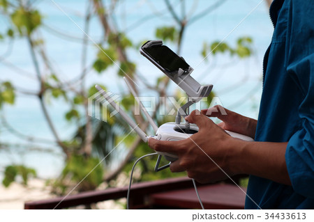 Men are using smartphones control drone camera. 34433613