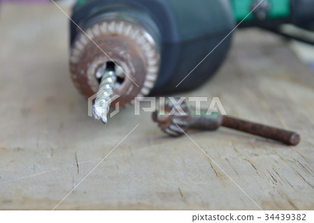 electric drill and chuck key on wooden board electric drill and chuck key on wooden board 34439382