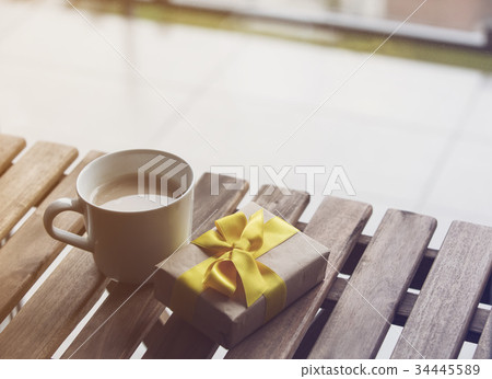 White cup of coffee or tea near a present gift 34445589