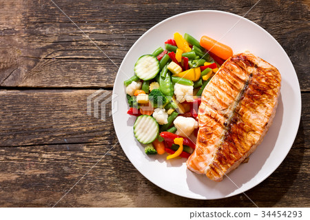 plate of grilled salmon steak with vegetables 34454293