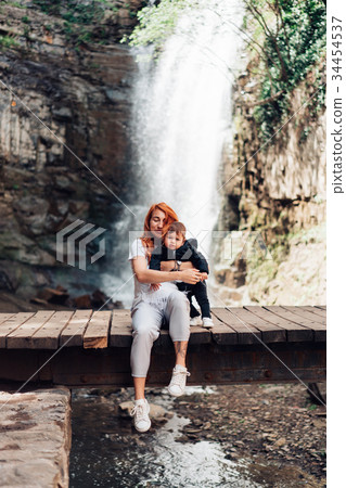 Mom and little son are sitting on the bridge Mom and little son are sitting on the bridge 34454537