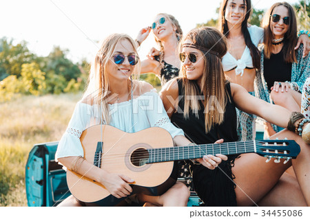Girls are sitting on the trunk with a guitar 34455086