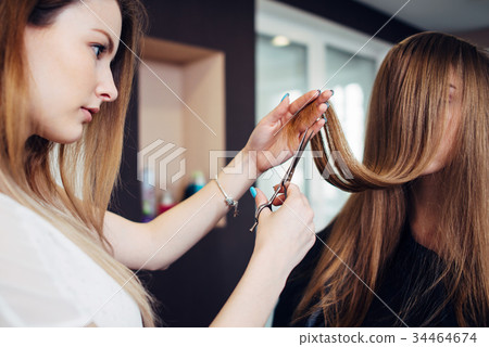 Hairdresser trimming the split ends of female Hairdresser trimming the split ends of female 34464674