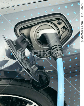 Electric vehicle being plugged in Electric vehicle being plugged in 34465028
