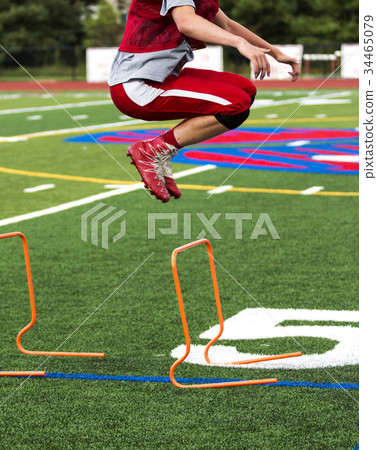 High school football player bounding over hurdles 34465079