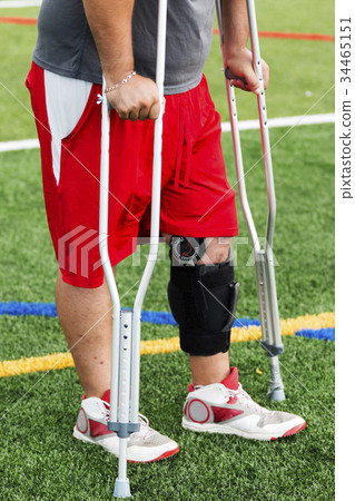 Injured athlete in a knee brace on crutches Injured athlete in a knee brace on crutches 34465151