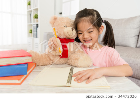 smiling little girl doing homework with her teddy smiling little girl doing homework with her teddy 34472026