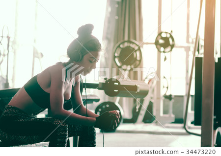 Asian woman sitting at gym club and listen music 34473220