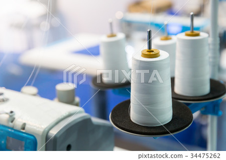 Spools of white threads on sewing machine, closeup 34475262