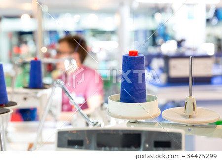 Spools of blue threads on sewing machine, factory 34475299