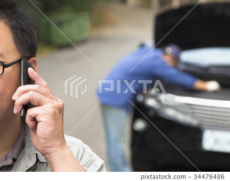 man Talking on Phone While Mechanic Fixes Car 34476486