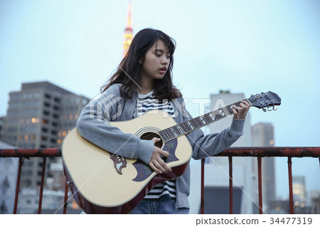 A woman playing the guitar A woman playing the guitar 34477319
