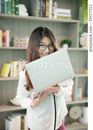 Business Asian woman holding a laptop in library 34477321