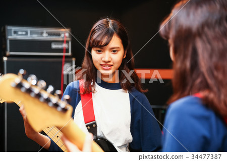 A woman playing the guitar 34477387