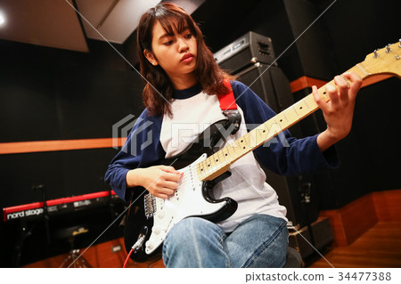 A woman playing the guitar A woman playing the guitar 34477388