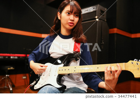 A woman playing the guitar A woman playing the guitar 34477441