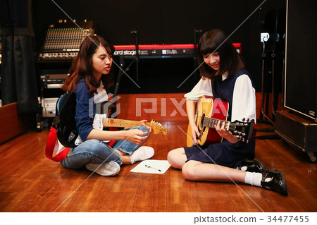 A woman playing the guitar 34477455