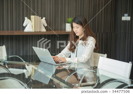 An Asian business woman using laptop in office An Asian business woman using laptop in office 34477506