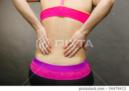 Woman with medical kinesio taping on back Woman with medical kinesio taping on back 34479413