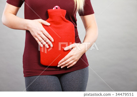 Girl having stomach ache, holding hot water bottle Girl having stomach ache, holding hot water bottle 34479551
